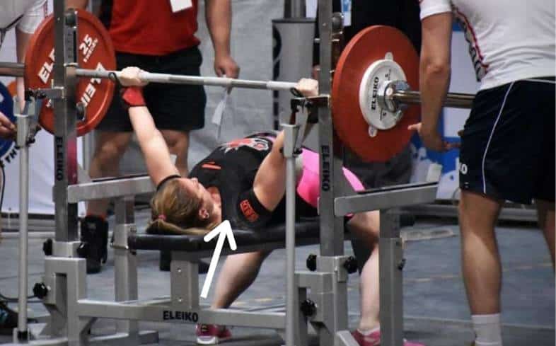 A powerlifter using leg drive to get as high as possible on their traps while laying on the bench press. 