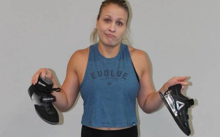 A lifting coach holds squat shoes for deadlifting.