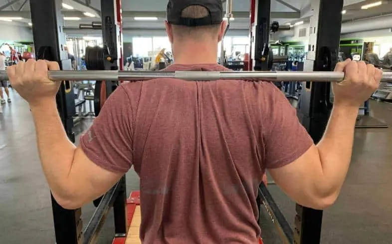 In high bar squats, the bar sits atop the traps just above the rear deltoid