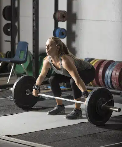 Strong female athlete preparing for heavy lift in grungy gym snatch grip deadlift