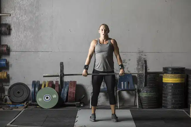 Strong young woman weight training in grungy gym snatch grip deadlift