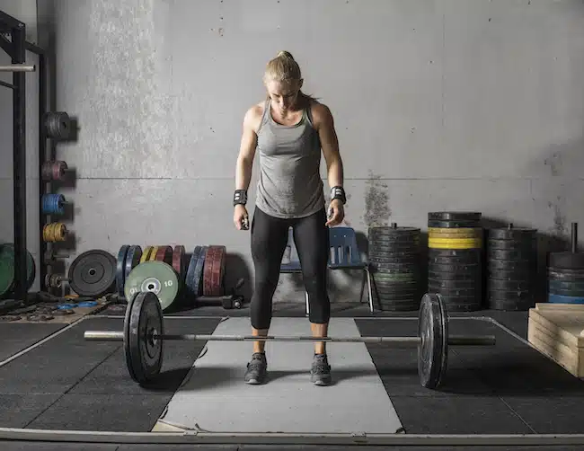 Young strong female weight lifter preparing to lift heavy barbell and snatch grip deadlift