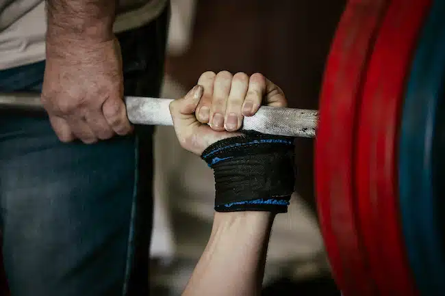 powerlifting bench press barbell hands of athlete powerlifter and coach