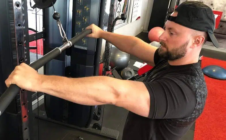 A powerlifting coach showing grip while discussing reasons to train triceps 2 days in a row.