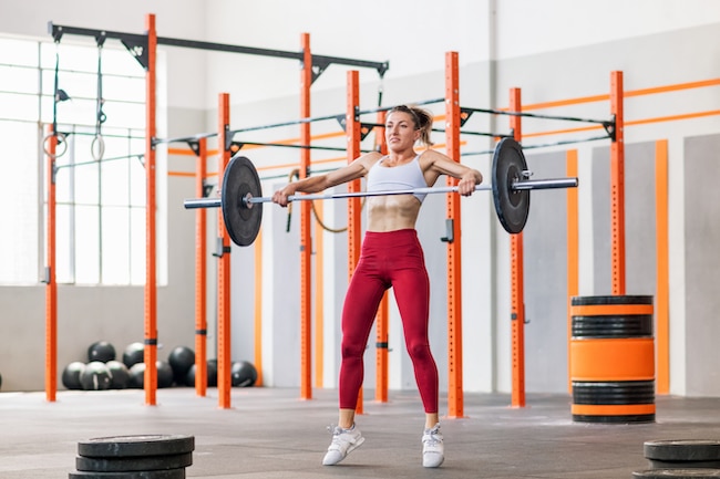 Fit muscular young woman performing a barbell snatch with olympic bar