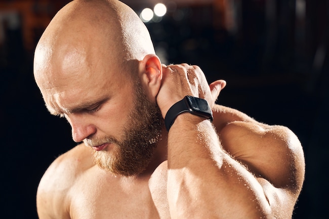 Handsome sportsman cringing from neck muscle soreness