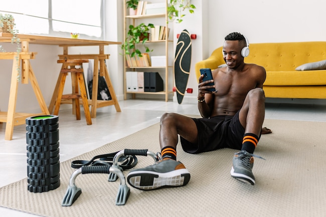 Athletic african man using mobile phone after workout routine at home