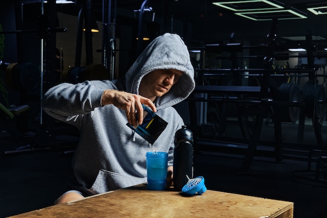 Man pouring energy sports supplement in bottle