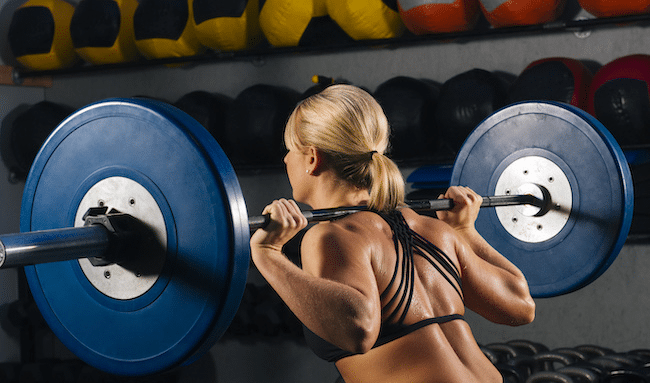 young-woman-squatting-with-barbell-on-shoulders-in-2022-03-08-00-13-46-utc