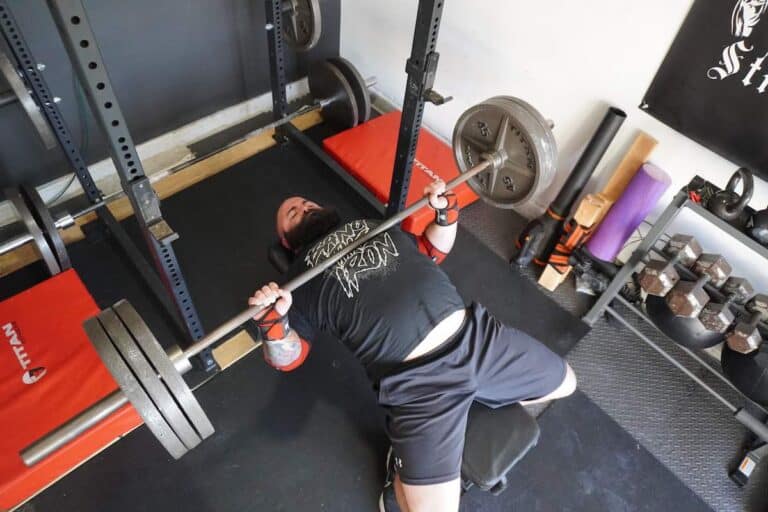 Coach Lucero does bench press with wrist wraps from his home gym.