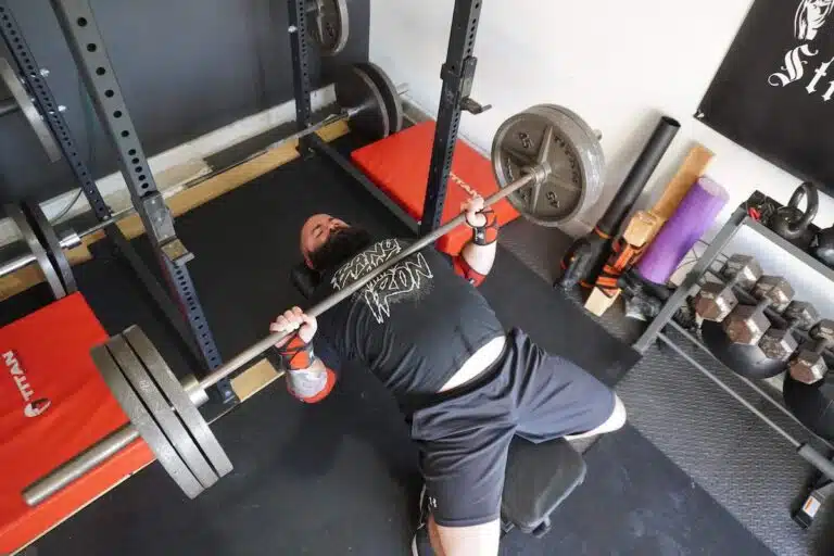Coach Lucero does bench press with wrist wraps from his home gym.