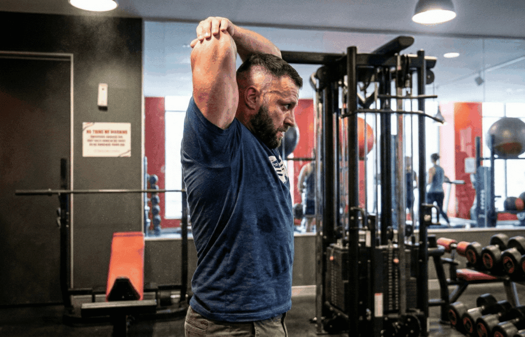 A lifter stretching his arms at the gym.