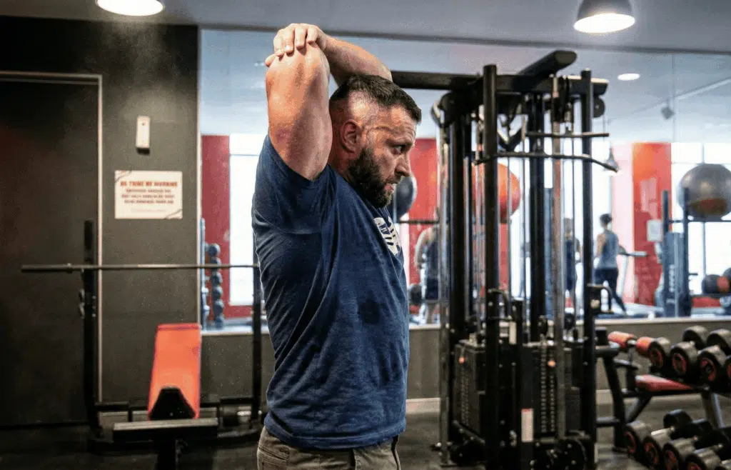 A lifter stretching his arms at the gym.