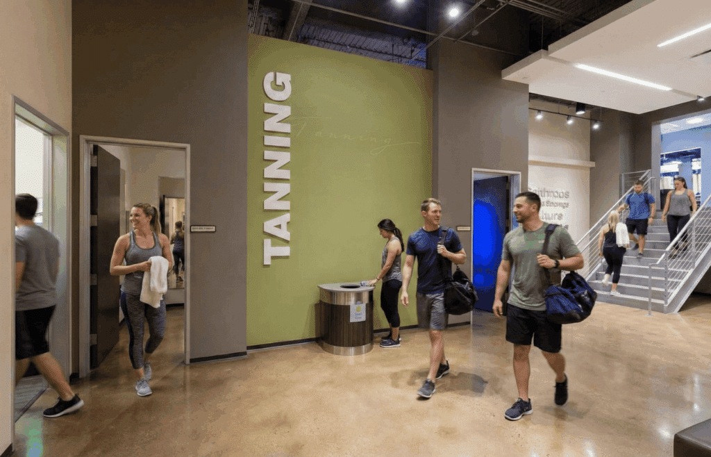 Gymgoers walking by tanning rooms at the gym.