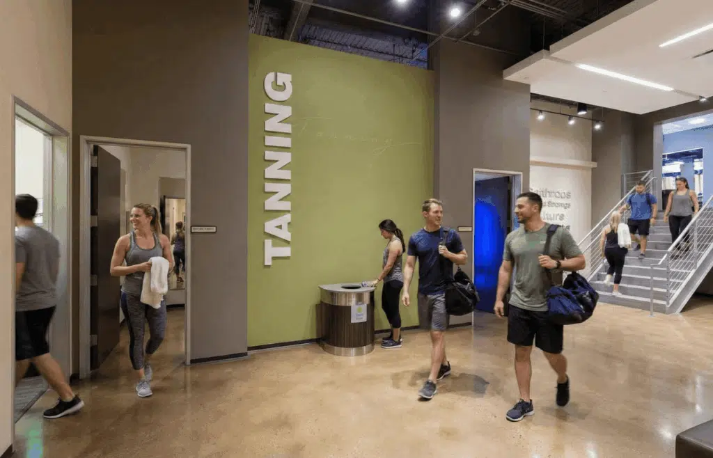Gymgoers walking by tanning rooms at the gym.