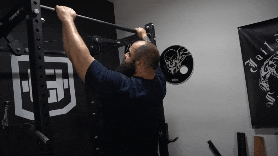 A strength and fitness coach showing how to do eccentric pull ups, focusing on controlled descent.