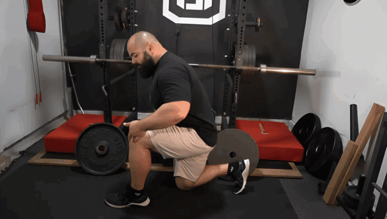 A professional strength coach shows the bottom position of a split squat.