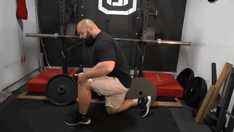 A professional strength coach shows the bottom position of a split squat for leg day.