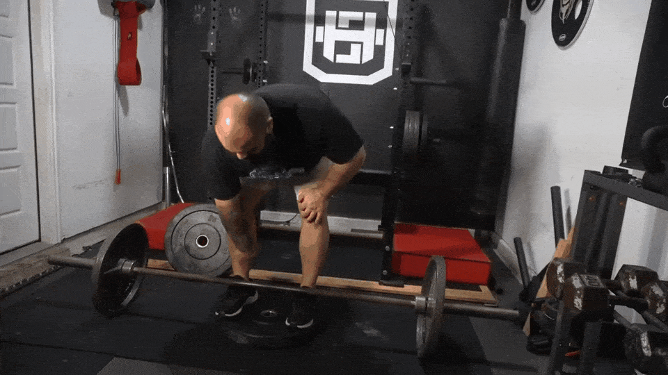 Strength coach showing how to do deficit deadlift, including the starting position and the top of the lift.