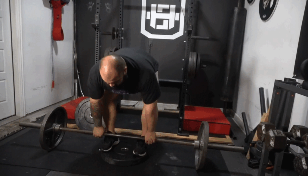 A strength coach shows the starting position for deficit deadlift.