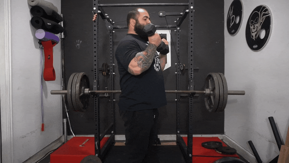 Coach Lucero talks about why we lean back during bicep curls. The caption text reads, " As you curl, you're gonna lean back and accommodate to the movement. And look how my arms are diagonal to the floor. I got all tension at the bottom of my lift, and now I got more tension at the top of my lift. So I'm manipulating my stance. To keep that bicep tense from start to finish."