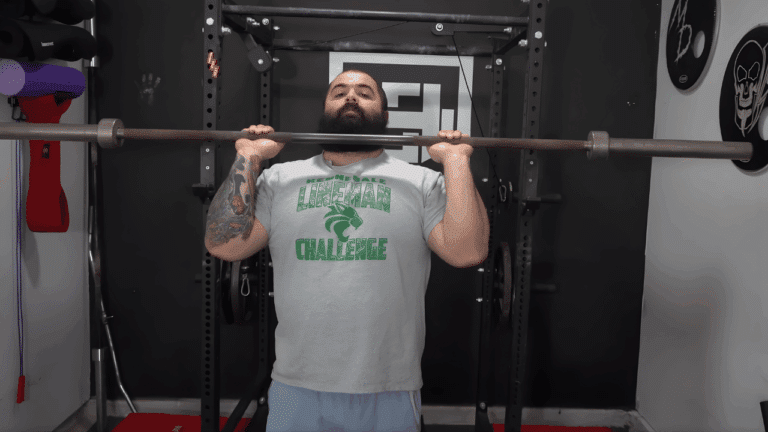 A powerlifting coach shows how to do military press.