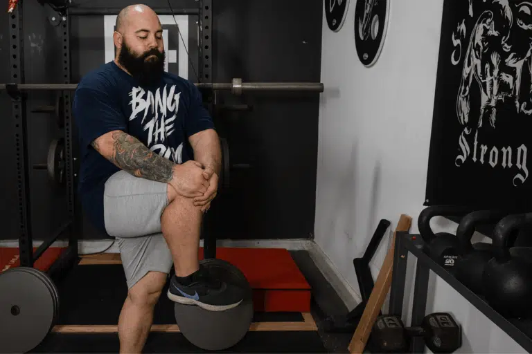 A coach explaining static vs dynamic stretching, does knee hugs.