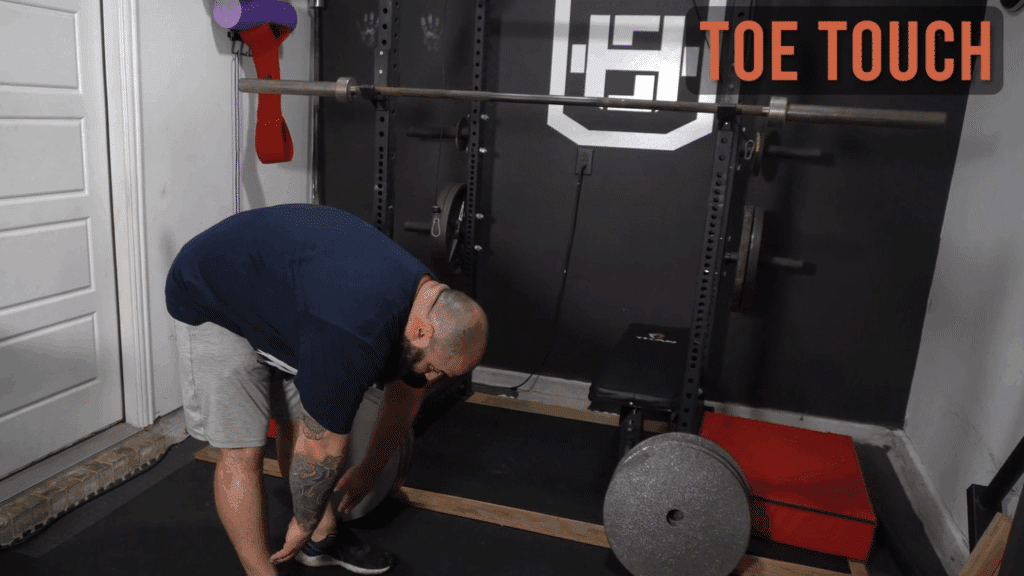 A strength coach shows how to do toe touches.