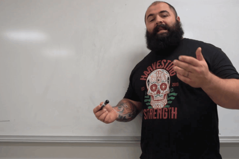 A strength coach in front of a whiteboard in a college classroom.