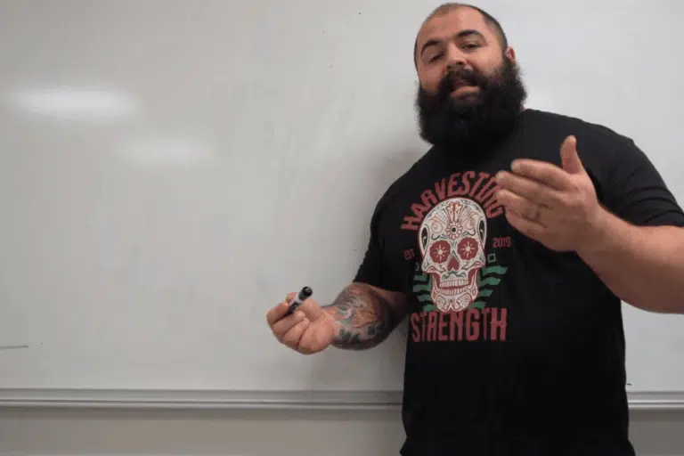 A strength coach in front of a whiteboard in a college classroom.